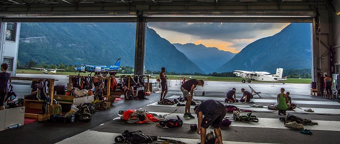 Skydivers in the hangar prepare parachutes before the jump