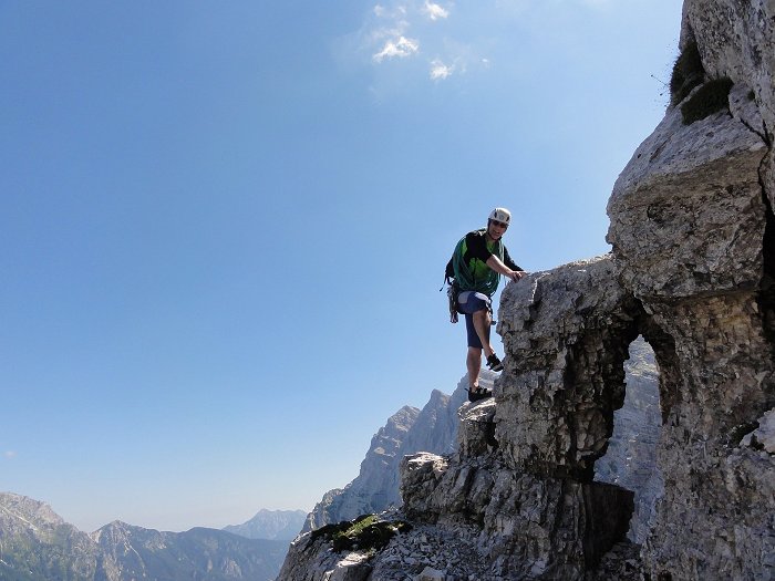 Alpinist v polni opremi se vzpenja po alpinistični smeri.