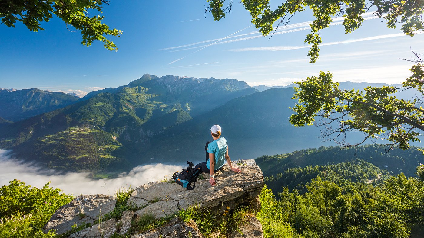 Pohodnica počiva na skali z razgledom na Dolino Soče