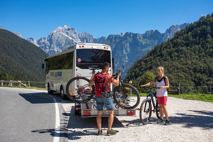 The cyclists were taken by bus to the mountains and are unloading the bikes from the trailer.