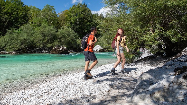 Die Wanderer wandern am sandigen Ufer des Flusses Soča entlang